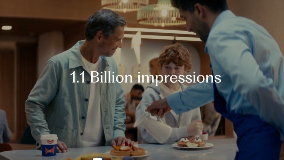 Frame from the Hilton EMEA sizzle: a family being served breakfast in a hotel restaurant, captioned 1.1 Billion impressions.